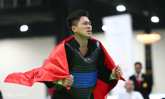 Nguyễn Tấn Sang nhăn nhó vì nén đau khi cầm cờ chạy mừng HC vàng pencak silat hạng dưới 80kg nam tại nhà thi đấu Impact ở Nonthaburi, Thái Lan sáng 17/12/2025. Ảnh: Đức Đồng