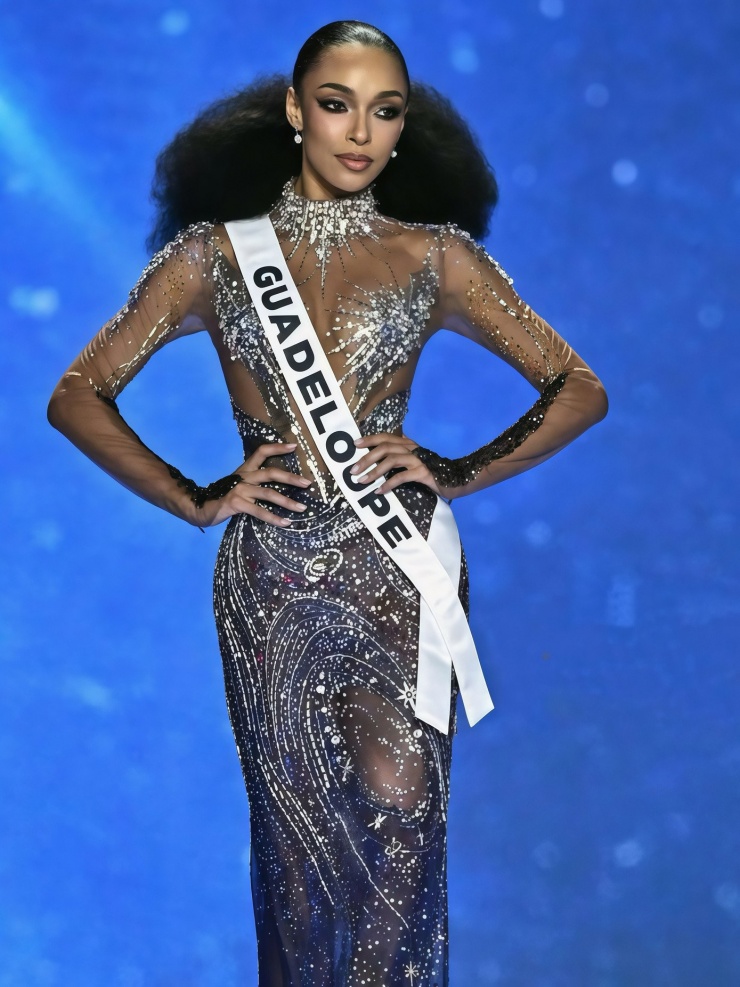 Xếp hạng ba là váy dạ hội của người đẹp Guadeloupe - Ophély Mézino mặc trong đêm chung kết Hoa hậu Hoàn vũ 2025 ở Thái Lan. Bộ váy do nhà thiết kế Việt Nam thực hiện, lấy cảm hứng từ vũ trụ trên nền chất liệu xuyên thấu. Những biểu tượng đặc trưng như ngôi sao, dải ngân hà được tạo thành bởi những viên đá đính kết cầu kỳ dọc thân váy.