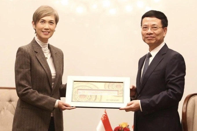 Bộ trưởng Nguyễn Mạnh Hùng tặng quà lưu niệm là một bộ tem Việt Nam cho Bộ trưởng Phát triển Kỹ thuật số và Thông tin Singapore, sáng 16/1. Ảnh: Doãn Mạnh