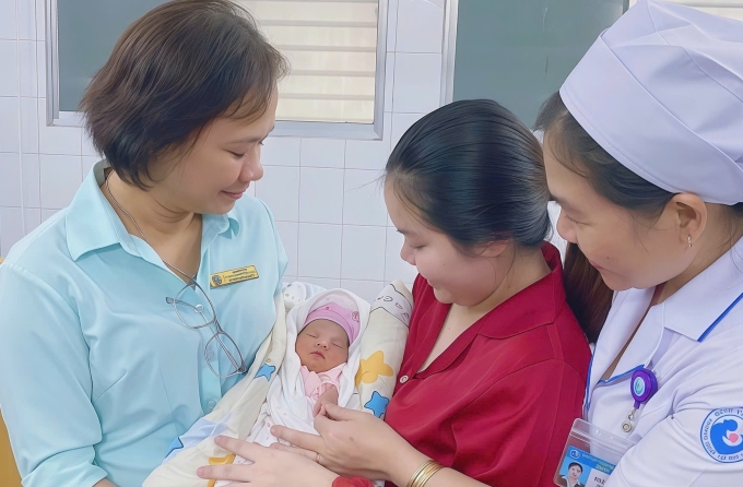 Bé gái trong vòng tay của người mẹ và các y bác sĩ khi xuất viện. Ảnh: Bệnh viện cung cấp