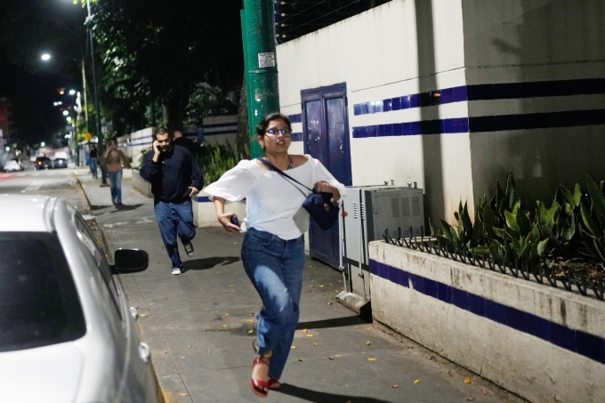 Mariana Camargo chạy khỏi khu vực vang lên tiếng nổ trên đường phố Caracas, Venezuela, ngày 3/1. Ảnh: AP