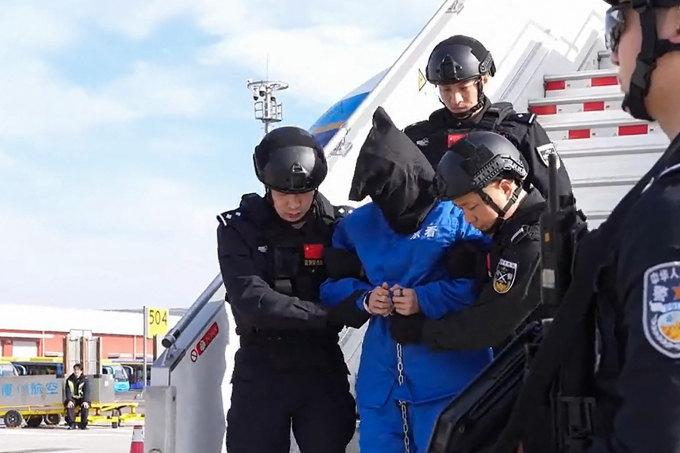Cảnh sát Trung Quốc áp giải Chen Zhi rời máy bay tại Bắc Kinh ngày 8/1. Ảnh: AFP