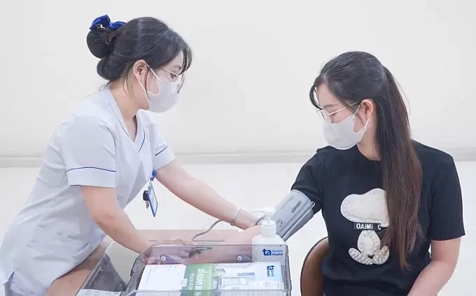 Nhân viên y tế đo huyết áp cho người đến khám. Ảnh: Bệnh viện Đa khoa Tâm Anh