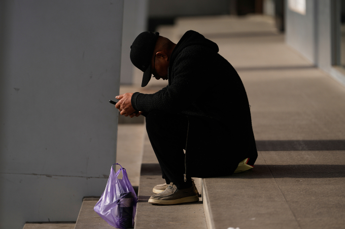 Một người đàn ông chăm chú nhìn vào điện thoại ở Bắc Kinh ngày 15/1. Ảnh: AP