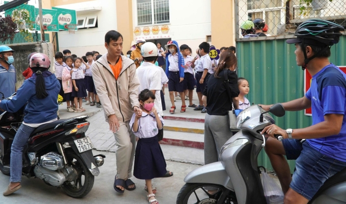 Phụ huynh mang cơm, đưa đón con về tại trường Tiểu học Nguyễn Văn Hưởng, ngày 30/1. Ảnh: Huế Xuân