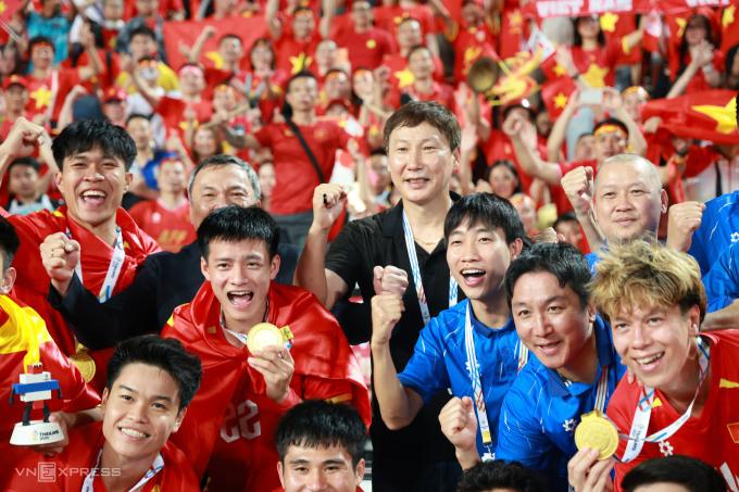 HLV Kim Sang-sik (áo đen giữa) cùng Việt Nam mừng HC vàng SEA Games 33 sau khi thắng Thái Lan 3-2 ở chung kết trên sân Rajamangala ở Bangkok, tối 18/12/2025. Ảnh: Đức Đồng