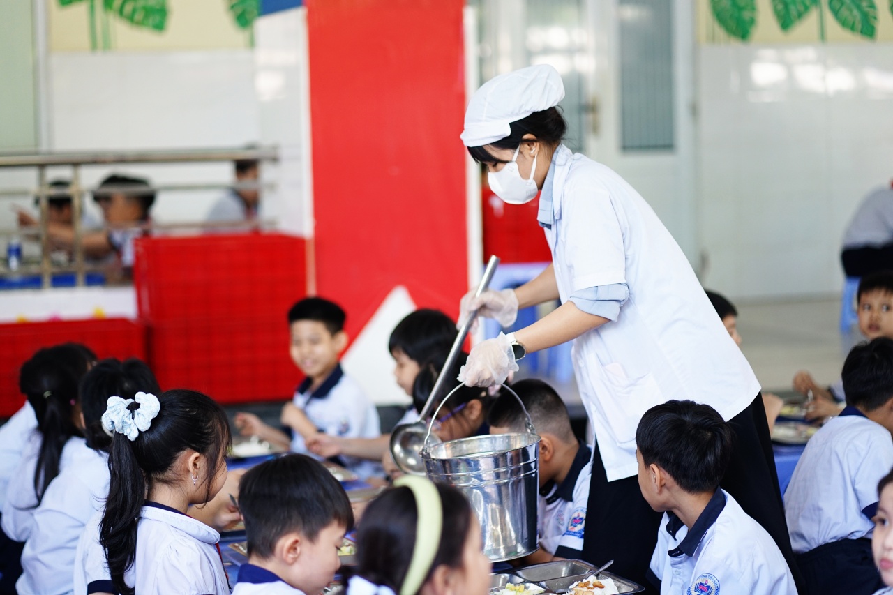 Cảnh tượng lạ tại cổng trường tiểu học ở TP.HCM mỗi buổi trưa: Phụ huynh tay xách cơm, người chờ đón con về nhà- Ảnh 2.