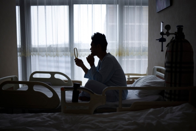 Bệnh nhân Xia Shurong soi gương sau ca phẫu thuật thẩm mỹ tại một phòng khám ở Bắc Kinh hồi tháng 7/2021. Ảnh: AFP