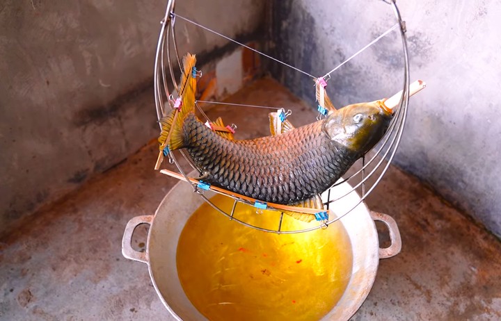 Về Hưng Yên tận thấy cỗ khao lão với cá chép nằm võng chế biến suốt 10 tiếng 4 Sau khi được định hình xong, cá chép để vào cái võng bằng inox khoảng gần một giờ cho cá se lại. Tiếp đó, khoảng 5 lít dầu ăn hoặc mỡ lợn được đổ vào chảo to sâu lòng đun nhỏ lửa cho sôi lăn tăn, võng cá đặt phía trên cách mặt chảo khoảng chừng 10-15cm.