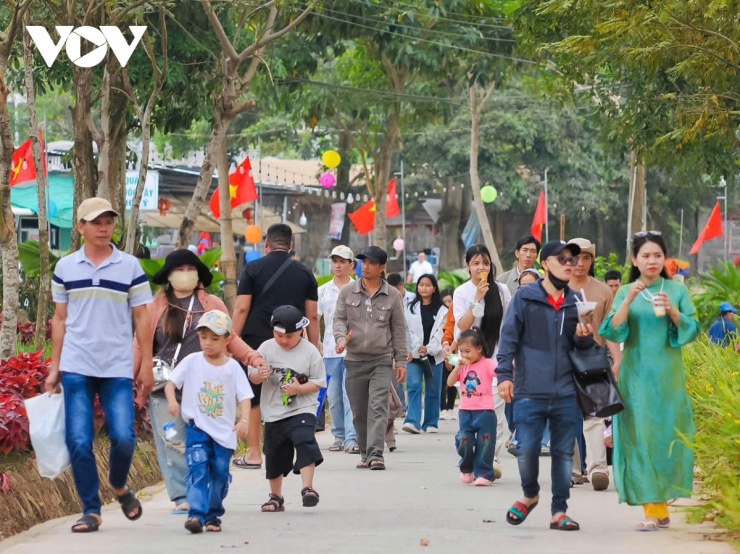 Hai bên đường, cờ đỏ sao vàng tung bay trong gió, tô điểm cho hành trình du xuân thêm phần trang nghiêm và phấn khởi. Không gian rực rỡ sắc xuân khiến mỗi bước chân hành hương càng thêm ý nghĩa.