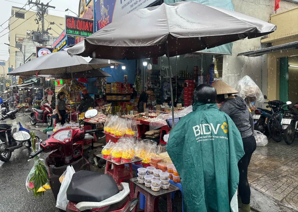 Người nội trợ "đội mưa" sắm đồ cúng trong dịp vía Thần Tài. Ảnh: THU HÀ THAN-TAI.jpg