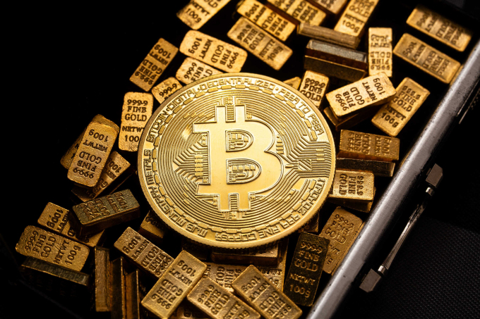 Đồng xu biểu trưng Bitcoin được đặt trong két sắt chứa những thỏi vàng 100g. Ảnh: CNBC