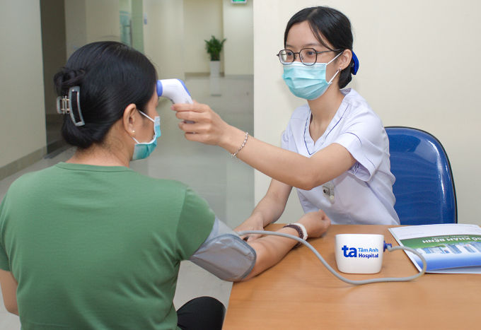 Chị Xuyến được điều dưỡng kiểm tra nhiệt độ, huyết áp trước khi vào xạ trị. Ảnh: Bệnh viện Đa khoa Tâm Anh