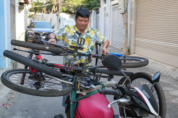 Anh Lê Khắc Dũng chằng buộc những chiếc xe đạp cũ vừa xin được lên xe máy, chở về kho để sửa trước khi tặng lại. Ảnh: Trường Hà