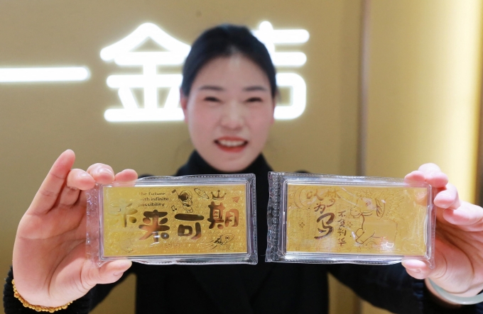 Nhân viên một cửa hàng vàng bạc ở Dương Châu, tỉnh Giang Tô, giới thiệu mẫu vàng thỏi mừng năm mới hôm 29/1. Ảnh: AFP