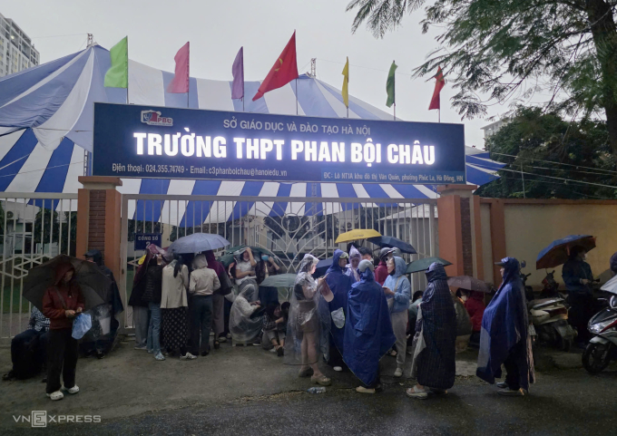 Phụ huynh đội mưa xếp hàng trước cổng trường THPT Phan Bội Châu, lúc 6h sáng 3/3. Ảnh: Thanh Hằng