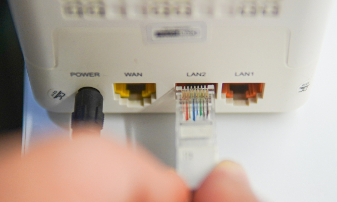 Một người đang cắm dây Ethernet vào một chiếc modem để kết nối Internet. Ảnh: Lưu Quý