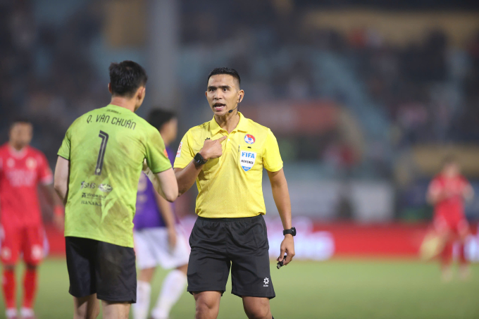 Trọng tài người Malaysia Nazmi Bin Nasaruddin (áo vàng) nhắc nhở thủ môn Quan Văn Chuẩn của Hà Nội FC. Ảnh: VPF
