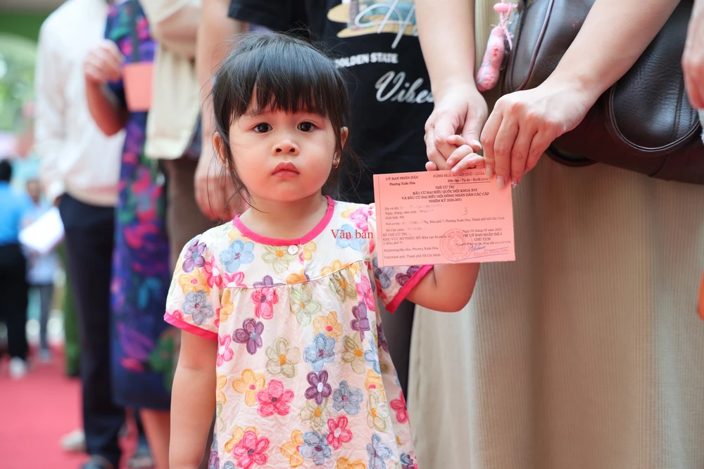 Hình ảnh bé gái theo mẹ đi bầu khiến nhiều người khen ngợi. Ảnh: LÊ THOA bau cu.jpg