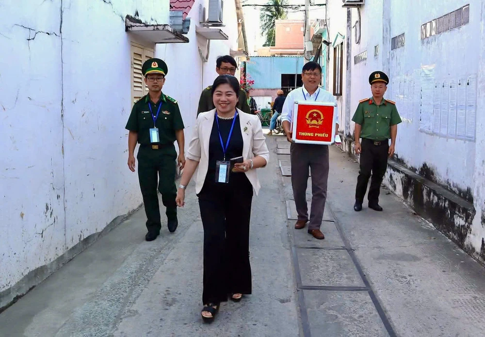 Bà Võ Thị Diễm Phượng - Đảng ủy viên, Phó Chủ tịch UBND xã Cần Giờ cùng tổ bầu cử mang thùng phiếu phụ đến nhà cử tri. Ảnh: MAI LINH khong-de-ai-lo-ngay-bau-cu-mang-thung-phieu-den-tan-nha-cu-tri-lon-tuoi-o-thieng-lieng-can-gio-1.jpg