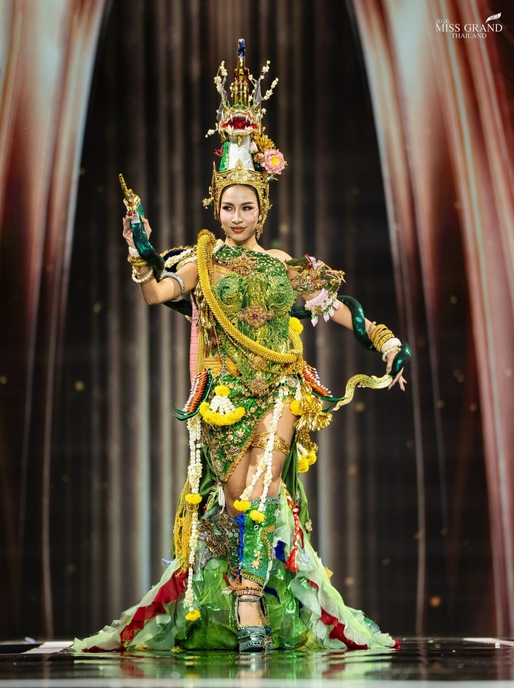 Thí sinh xiếc khỉ, trườn bò trên sân khấu Hoa hậu Hòa bình 5 Đại diện tỉnh Nong Khai mang đến bộ trang phục thể hiện sự thanh lịch và sức mạnh của niềm tin vùng lưu vực sông Mekong, tỉnh Nong Khai. Bộ trang phục màu xanh ngọc lục bảo và vàng lấy cảm hứng từ Naga, được tô điểm bằng đầu và vảy Naga được chế tác tinh xảo, kết hợp nghệ thuật đương đại Thái Lan.