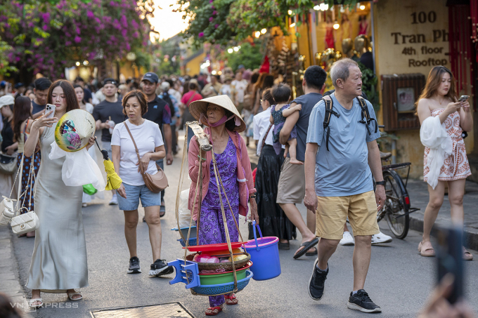 Một gánh hàng rong giữa dòng du khách trên phố cổ Hội An, chiều 25/3. Ảnh: Nguyễn Đông