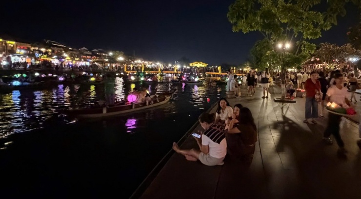 Du khách thoải mái ngồi bệt trên vỉa hè ngắm cảnh sông Hoài trong đêm.