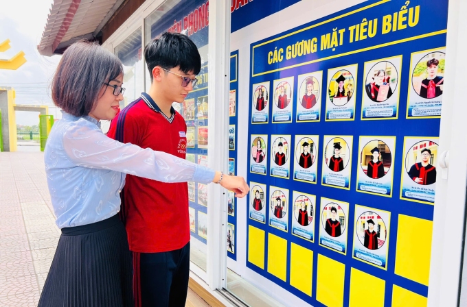 Đạt cùng cô giáo bên bảng vinh danh học sinh tiêu biểu của trường. Ảnh: Nhà trường cung cấp