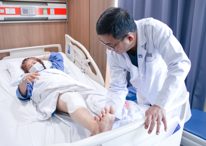 Bác sĩ Tuấn thăm khám cho bà Ngọt sau phẫu thuật thay khớp bằng robot. Ảnh: Bệnh viện Đa khoa Tâm Anh