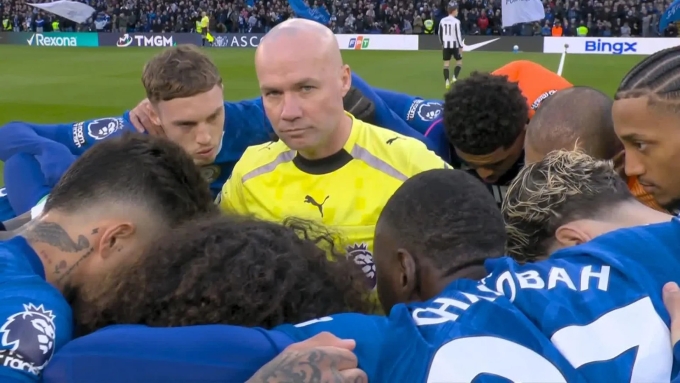 Trọng tài Tierney (vàng) đứng giữa vòng tròn được tạo bởi các cầu thủ Chelsea, trước trận đấu ở vòng 30 Ngoại hạng Anh, trên sân Stamford Bridge, London, Anh hôm 14/3. Ảnh: Reuters