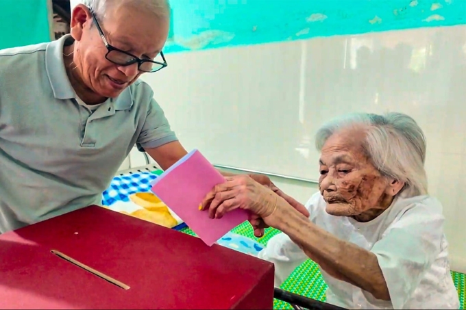 Cụ Đặng Thị Lãm, sinh năm 1910, tự tay bỏ lá phiếu vào thùng. Ảnh: Vinh Đệ