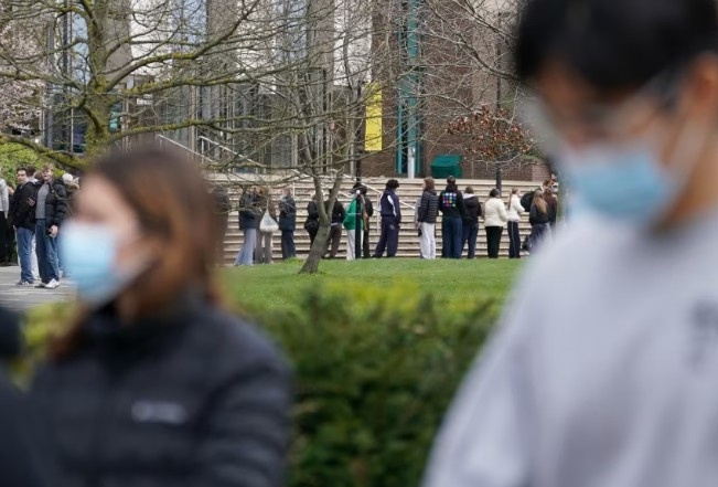Các sinh viên xếp hàng chờ nhận thuốc kháng sinh bên ngoài một tòa nhà tại Đại học Kent ở Canterbury, Anh, hôm 16/3. Ảnh: Gareth Fuller/PA/AP