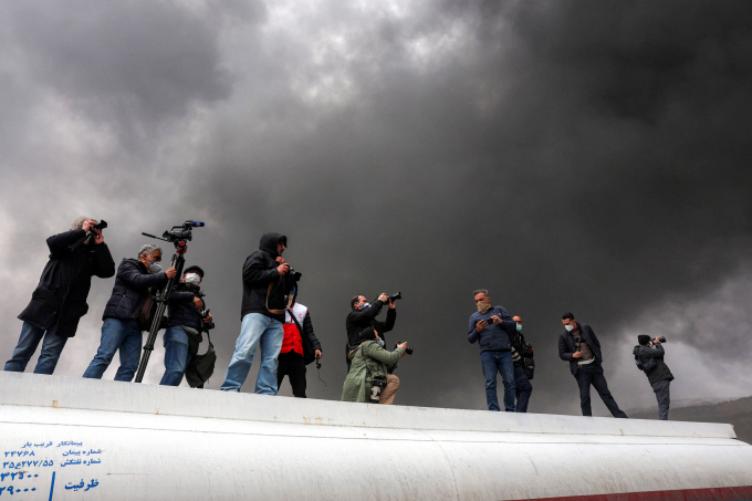 Phóng viên chụp ảnh mây đen độc hại sau khi cơ sở dự trữ dầu Iran bị không kích, ngày 8/3. Ảnh: AFP