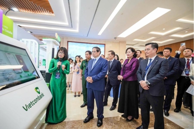 Bà Đoàn Hồng Nhung, Giám đốc Khối bán lẻ Vietcombank giới thiệu với Thủ tướng Chính phủ, Thống đốc NHNN và các đại biểu tính năng đăng ký chữ ký số trên app VCB Digibank thông qua kết nối với Cổng ký số tập trung từ xa VNeID(Năm 2025). Ảnh: Vietcombank