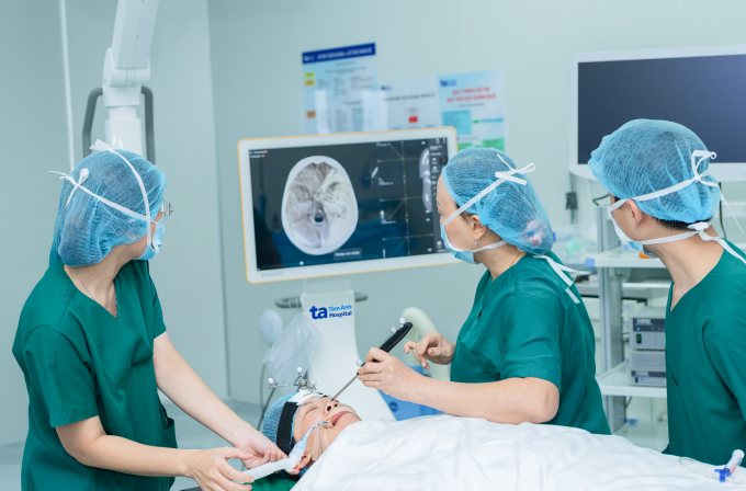 GS Chung Thủy (thứ hai bên phải) dùng đầu dò để kiểm tra kết nối của cấu trúc giải phẫu thực tế với hình ảnh CT trên màn hình định vị ứng dụng AI. Ảnh: Bệnh viện cung cấp