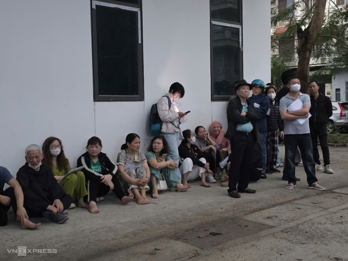 Phụ huynh trú mưa ở đối diện cổng trường THPT Phan Bội Châu, 6h sáng 3/3. Ảnh: Thanh Hằng