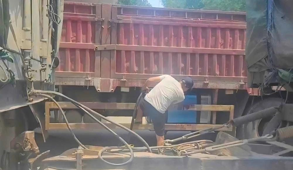 Tài xế xe tải bơm dầu vào một thùng bằng inox gắn dưới gầm xe để chở sang Lào. Ảnh: MINH TRƯỜNG. xang-dau-lao-bao-hai-quan-quang-tri.jpg