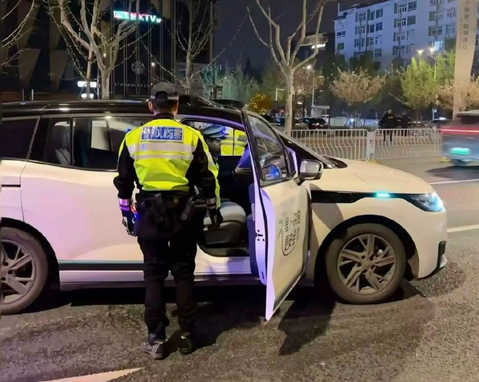 Cảnh sát tiếp cận một trong số các xe gặp sự cố của Apollo Go tại Vũ Hán, đêm 31/3. Ảnh: Weibo