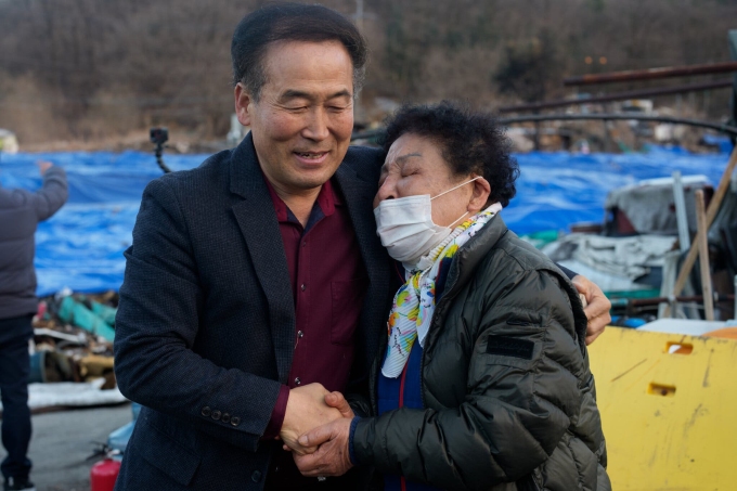 Mục sư an ủi bà Ko, người trắng tay sau trận hỏa hoạn hồi tháng 1 tại làng Guryong. Ảnh: NYT