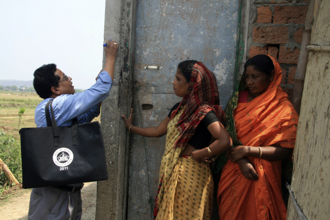 Nhân viên điều tra dân số (trái) đánh dấu một ngôi nhà ở thành phố Guwahati, bang Assam, sau khi thu thập thông tin hồi tháng 4/2010. Ảnh: Reuters