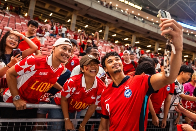 Tiền đạo Ikhsan Fandi chụp ảnh cùng người hâm mộ Singapore sau trận thắng Bangladesh 1-0 trên sân Kallang, Singapore, ở vòng loại Asian Cup 2027 tối 31/3/2026. Ảnh: FAS