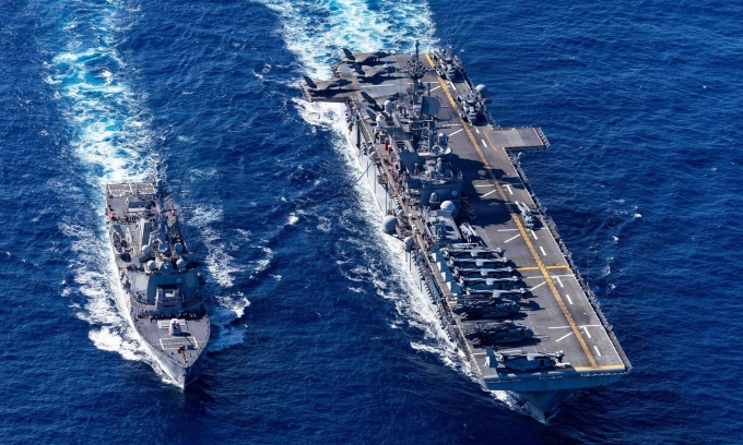 Tàu tấn công đổ bộ USS Tripoli (bên phải) đi qua eo biển Singapore hôm 17/3. Ảnh: CENTCOM