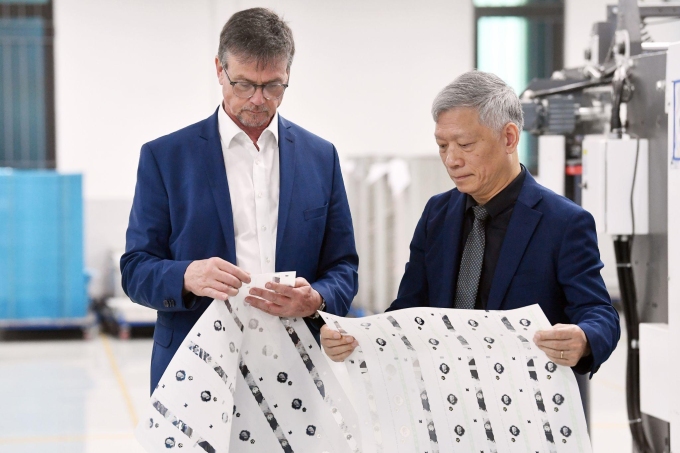 Ông Lương Ngọc Anh (phải), Tổng giám đốc Công ty TNHH Công nghệ cao Polymer Q&T, và Phó tổng giám đốc tập đoàn Leonhard Kurz Stiftung & Co. KG bên vật liệu in tiền polymer do Q&T sản xuất. Ảnh: Polymer Q&T