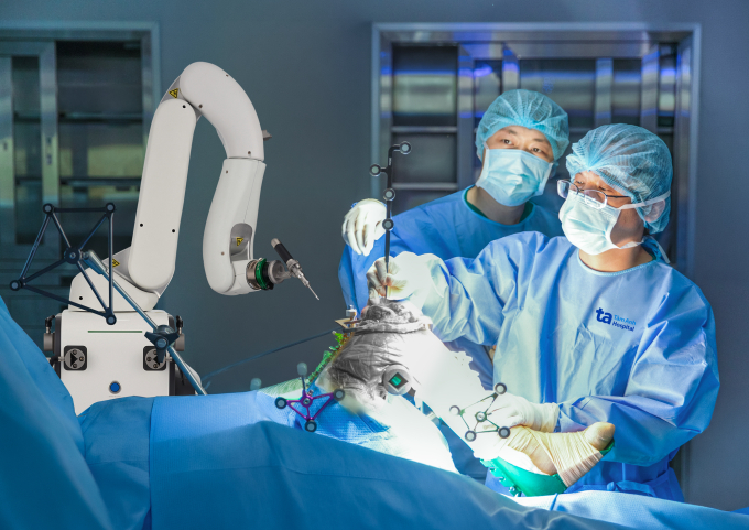 Bác sĩ Bảo (phải) thay khớp gối cho bà Hương dưới sự hỗ trợ của robot AI Cuvis-Joint. Ảnh: Bệnh viện Đa khoa Tâm Anh