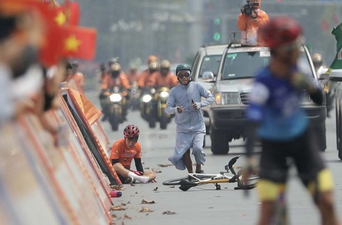 Người dân Nghệ An (mặc áo chống nắng) chạy tới giúp đỡ cua-rơ Nguyễn Văn Bình sau khi anh ngã ở đích đến chặng 5 giải xe đạp toàn quốc tranh Cup Truyền hình HTV 2025 từ Thanh Hóa đi Nghệ An, trưa 7/4. Ảnh: Như Huy